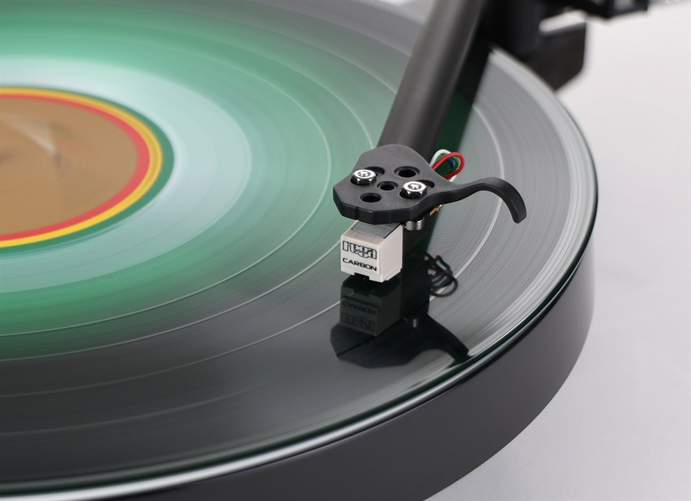 Close-up of the Rega Replay playing: the Rega Carbon cartridge on the RB110 tonearm, tracking a spinning record.